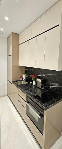 une cuisine avec des armoires blanches et des comptoirs noirs dans l'établissement Appartement Luxe Nice Plage, à Nice