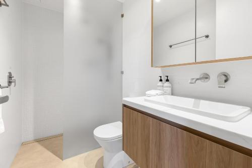 a white bathroom with a sink and a toilet at Bokarina Beach Apartments, an Ascend Collection Hotel in Bokarina