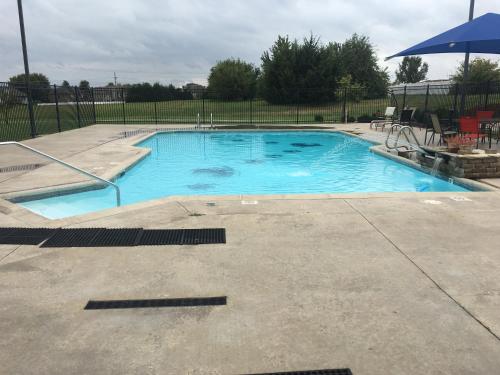 ein großer blauer Pool mit Sonnenschirm in der Unterkunft Paola Inn and Suites in Paola