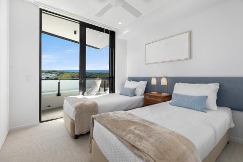 a bedroom with two beds and a large window at Bokarina Beach Apartments, an Ascend Collection Hotel in Bokarina
