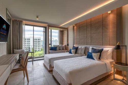 a hotel room with two beds and a large window at Howard Johnson by Wyndham Pattaya JC in Na Jomtien