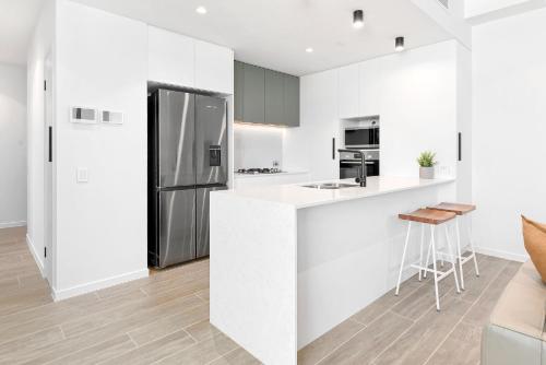 a white kitchen with a stainless steel refrigerator at Bokarina Beach Apartments, an Ascend Collection Hotel in Bokarina