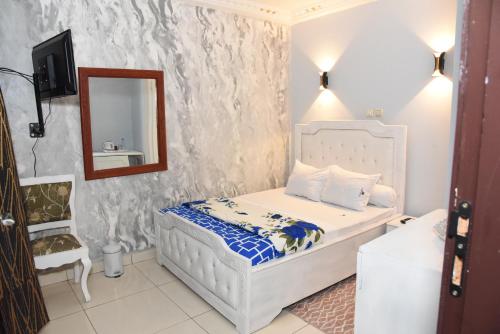 a small bedroom with a bed and a mirror at Gamo Hotel in Yaoundé