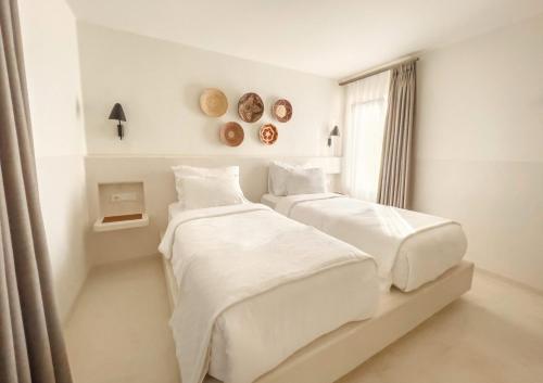 two beds in a white room with a window at Pilos Suites in Turunc