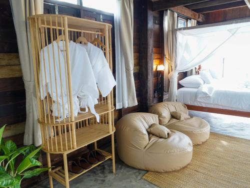 a room with a crib and a bed and two ottomans at RoomQuest THEVA Resort Koh Samui in Koh Samui 