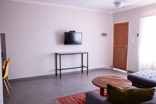 a living room with a table and a tv on the wall at Emerald Bed&Breakfast in Windhoek
