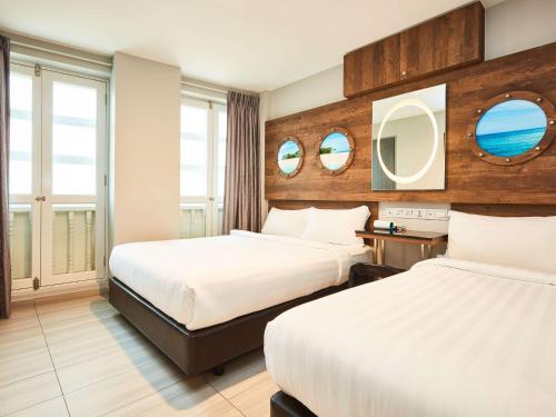 a hotel room with two beds and two mirrors at ibis budget Singapore Selegie in Singapore