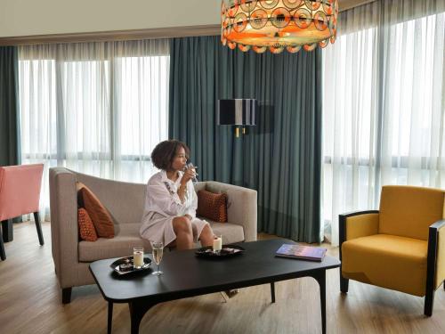 a woman sitting on a couch talking on a cell phone at Pullman Nairobi Upper Hill in Nairobi