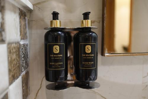 two black bottles of soap sitting on a wall at Pride Premier Solitaire in Dehradun