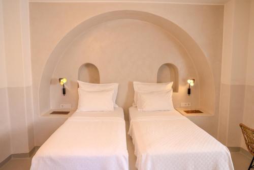 two beds in a room with an arched wall at Pilos Suites in Turunc