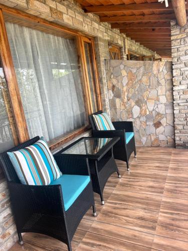 a screened porch with two chairs and a glass table at Kasar Himalaya Holiday Resort, Binsar Rd in Almora