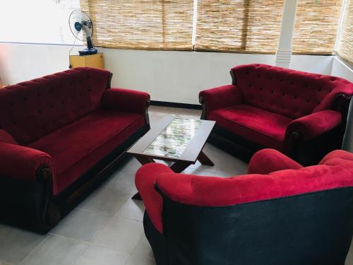 a living room with two red couches and a table at Dream View Hotel in Polonnaruwa