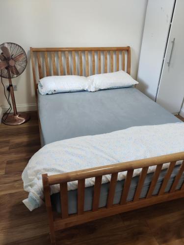 a bed with a wooden frame and a fan at Chiltern Nursuries in Amersham