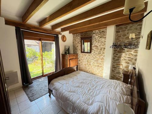 une chambre avec un lit et un mur en pierre dans l'établissement Maison Périgourdine 14 personnes avec piscine, à Busserolles