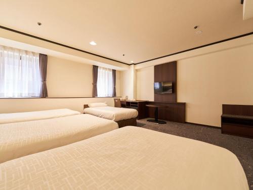 a hotel room with three beds and a desk at Princess Garden Hotel in Nagoya