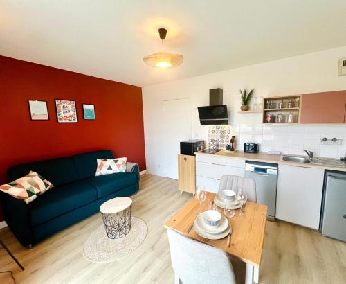 a living room with a blue couch and a kitchen at Le Courvoisy, Studio avec piscine, près Groupama Stadium et Salle Arena in Meyzieu