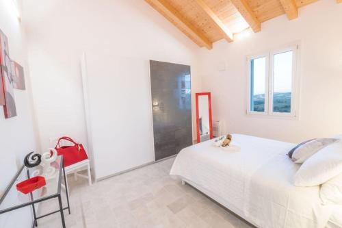 a white bedroom with a bed and a red chair at CASAL DEL SOLE - Il Gelso in Montefelcino