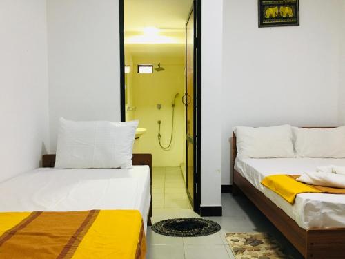 two beds in a room with a shower at Dream View Hotel in Polonnaruwa