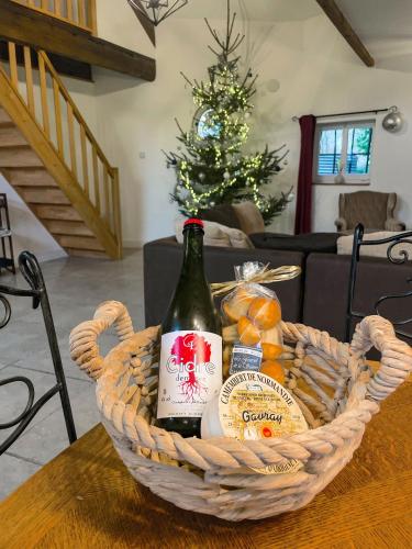 a basket of wine and oranges on a table with a christmas tree at La Maison Gavraise in Gavray
