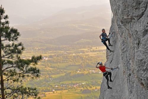 two people are climbing on a rock formation at Apartmani Grot Pale in Pale