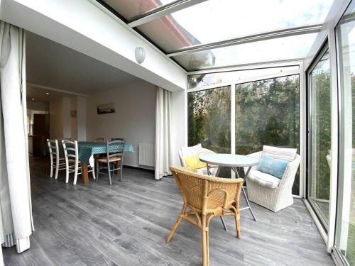 une véranda avec une table et des chaises sur une terrasse dans l'établissement Petite maison VUE MER face à la plage Trestraou PERROS-GUIREC - Réf 914, à Perros-Guirec