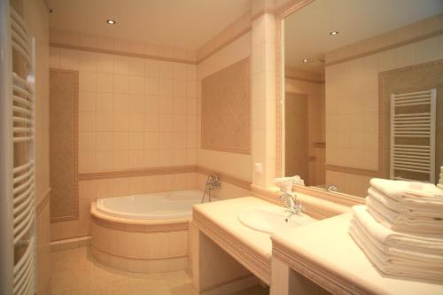 a bathroom with a tub and a sink and a mirror at Slunecni Lazne Apartments in Karlovy Vary