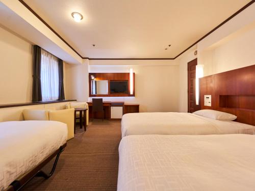 a hotel room with two beds and a desk at Princess Garden Hotel in Nagoya
