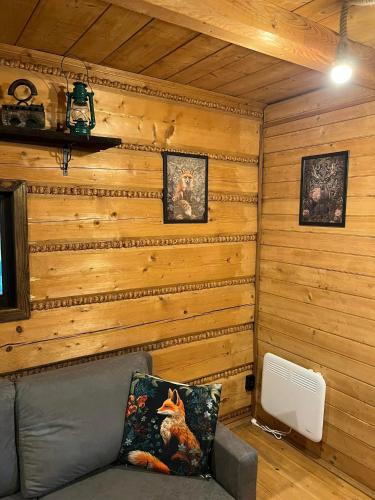 a living room with a couch in a wooden wall at Chata pod lasem in Myślenice