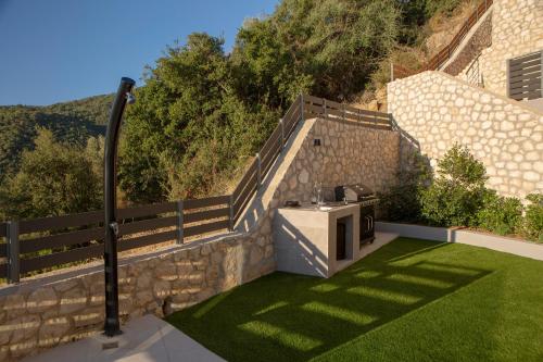 a small garden with a stone wall and a grill at Oriens Villas in Palaiokhóri