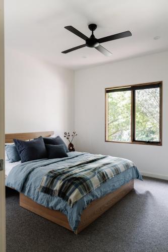 a bedroom with a bed with a ceiling fan at The Wooden House in Bright