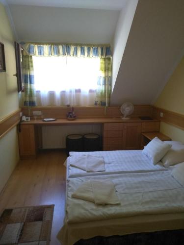a bedroom with a bed and a desk and a window at Odvaskő Panzió in Ugod