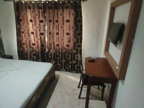 a bedroom with a bed and a desk and a television at New Green Horse Hotel in Cotonou