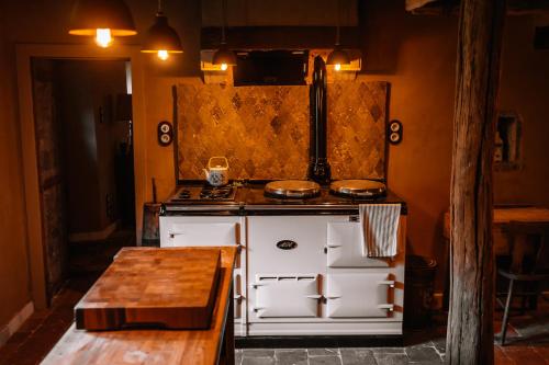 a kitchen with a stove and a wooden table at La Petite Foret 17th Cent Cottage Near Durbuy in Clavier