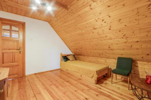 a bedroom with a bed and a green chair at Rustykalny domek pod Ślężą in Sulistrowiczki