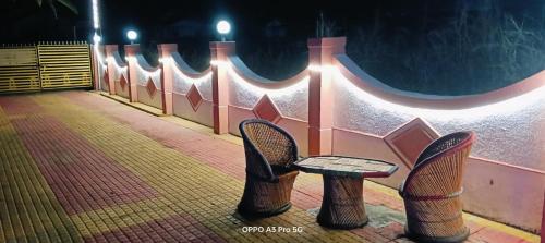 two chairs and a table in front of a wall at Humdum Holiday Homes 1 in Neral