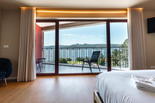 a bedroom with a bed and a balcony with a view at Belas Vistas Hotel in Montalegre