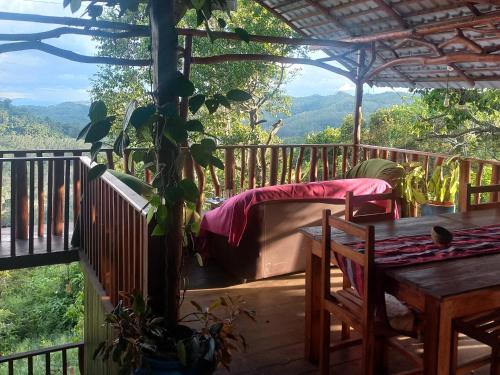 a porch with a bed and a table on a deck at Aybish Resort - Diyaluma in Diyaluma
