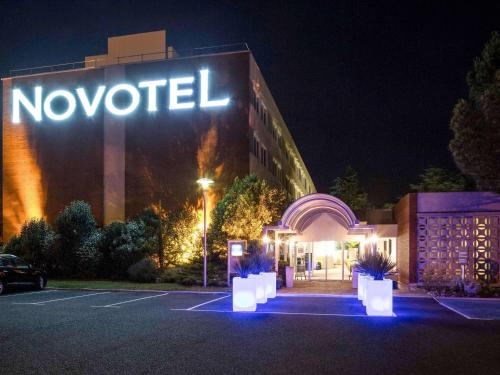 a hotel with a sign on the side of it at night at Novotel Toulouse Purpan Aéroport in Toulouse