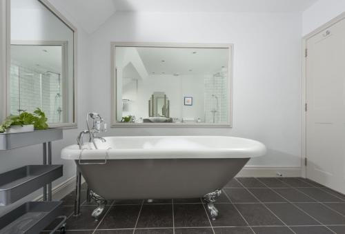 a white bath tub in a bathroom with a mirror at Henscath House in Helston