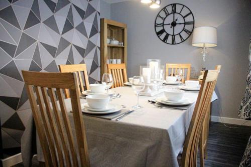 a dining room table with chairs and a clock on the wall at Beach house in Newcastle upon Tyne