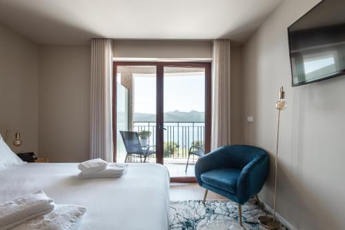 a bedroom with a bed and a chair and a window at Belas Vistas Hotel in Montalegre
