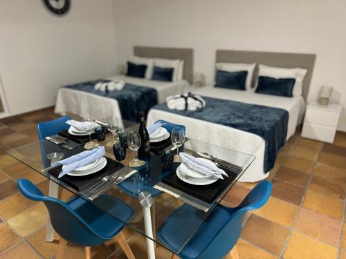 a room with two beds and a table with blue chairs at Alforra Residence 2-Centro-Praias-Levadas in Câmara de Lobos