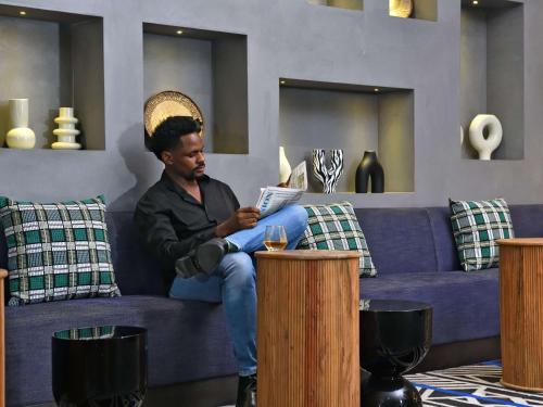 a man sitting on a couch reading a book at Novotel Nairobi Westlands in Nairobi