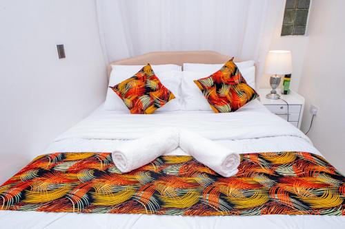 a white bed with a colorful blanket and pillows at Arabella Bloom - Chic 1-Bedroom Apartment near Waterfront Mall Karen in Karen