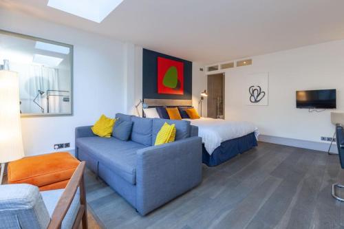 a living room with a blue couch and a bed at Oxford Garden Luxury Studio in Oxford