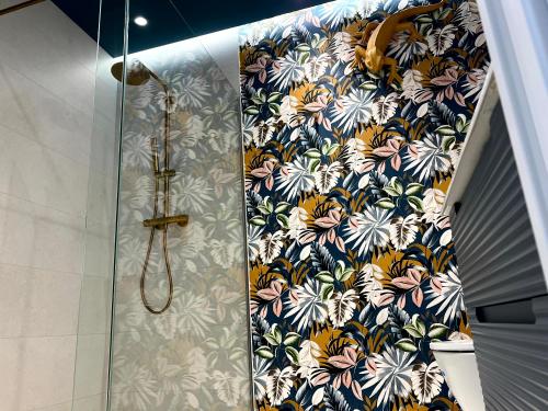 a shower in a bathroom with a floral wallpaper at CHAPITELES Catedral in Burgos