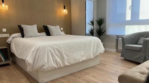a bedroom with a large white bed and a chair at CHAPITELES Catedral in Burgos