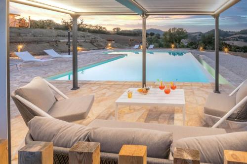 a pool with couches and a table next to at CASAL DEL SOLE - L'Ulivo in Montefelcino