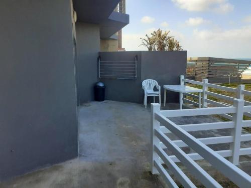 a balcony with a table and a fence at Seaside Escape in Gqeberha