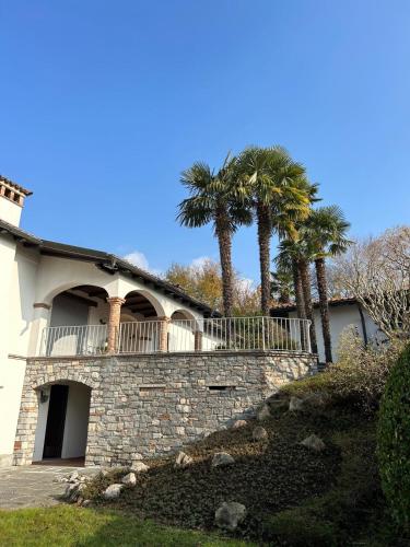 a house with palm trees behind a stone wall at 2 bedroom apt near Como lake in Morbio Inferiore